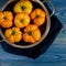 Washed various tomatoes in a colander on a wooden background