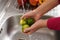 Washing an apple to fight the Coronavirus Outbreak, side view of a person who disinfects an apple by pouring water over it in the