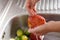 Washing an apple to fight the Coronavirus Outbreak, side view of a person who disinfects an apple by pouring water over it in the