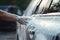 Washing car with soap and water. Close up of female hand washing car, Manual car wash with white soap, and foam on the body.