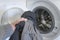 washing dark clothes. man\'s hand folds clothes into an open washing machine