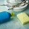 Washing dishes with special tool, yellow sponge and plates in the foam