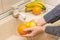 Washing fruits and food in the sink on kitchen. Hands washing orange and lemon