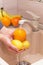 Washing fruits and food in the sink on kitchen. Hands washing orange and lemon