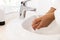 Washing hands of biracial woman in bathrobe in sunny bathroom