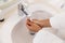 Washing hands of biracial woman in bathrobe in sunny bathroom