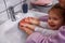 Washing hands is funny- mother and smiling kid girl wash hands w