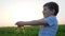 Washing hands of tiny boy and water splash in green field on background sky in dawn