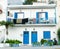 Washing hanging from balcony of typical blue doors and shutters against whitewashed walls of Greek island architecture