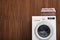 Washing machine and laundry basket with towels near wooden wall