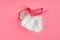 Washing powder for cleaning cloth pouring out of plastic measuring spoon lies on pink countertop in laundry