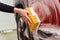 Washing a red car with a foamy yellow sponge. Woman& x27;s hand washing a car at the car wash