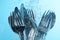 Washing silver cutlery in water on light blue background