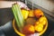 Washing vegetables. Hands in pink gloves washing vegetables in yellow bowl under water stream in sink. Woman  cleaning fresh