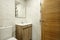 Washroom with white exposed brick walls with wooden vanity