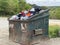 Waste dumpster at a county dump overflowing clothes and bags