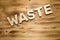 WASTE word made of wooden block letters on wooden board