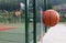 Wastebasket in the shape of a basketball ball on a footpath near outdoor sports club