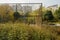 Wasted fenced basketball court in weeds before apartments in sun