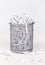 Wastepaper basket with papers lying around over white background