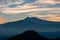 Watching beautiful sunset behind volcano Mount Etna near Castelmola, Taormina, Sicily. Clouds with vibrant red orange colors