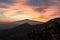 Watching beautiful sunset behind volcano Mount Etna near Castelmola, Taormina, Sicily. Clouds with vibrant red orange colors