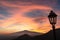 Watching beautiful sunset behind volcano Mount Etna near Castelmola, Taormina, Sicily. Clouds with vibrant red orange colors