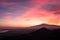 Watching beautiful sunset behind volcano Mount Etna near Castelmola, Taormina, Sicily. Clouds with vibrant red orange colors