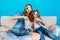 Watching movie in 3D glasses of happy mother and her daughter in jeans clothes on couch  on blue background