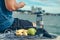 Water bottle, banana, earphone, green apple and towel on the ground beside young man rest after exercise and playing mobile phone