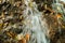 Water cascades on a mountain river with fallen autumn leaves