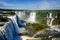 Water cascading over the Iguacu falls with rainbow in foreground