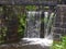 Water cascading over old wooden lock gates on the rochdale canal overgrown with plants and ferns in a rural woodland setting near