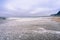 Water covering a sandy beach on the Pacific Ocean coastline on a foggy afternoon, California