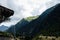 Water dripping over a mountain tunnel with power lines, mountain forest and puffy clouds above