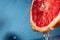 Water drips from half a grapefruit. Splashes and drops fly from a piece of grapefruit symbolizing the brightness and freshness of