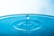 Water drop on blue background. Blue water surface with splash. Clear Waterdrop with circular waves. Splashes closeup. Water splash