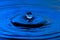 Water drop close up with concentric ripples colourful blue surface