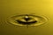 Water drop close up with concentric ripples colourful yellow surface