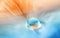 Water drop on feather on turquoise orange blurred background.