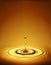 Water droplets creating ripples in amber water
