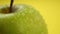 Water drops close-up on a green apple. Spraying fresh fruit in slow motion. Refreshing