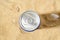 Water drops on a cold beer or soda can top agains sea sand on a sunny day. Drinking on the go beverages in aluminum cans with pull