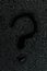 Water drops on flat black rubber surface with the inscription - question mark
