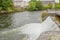 Water entering the Corrib river through a small dam forming a waterfall, calmly flowing water