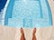 Water, feet and above man swimmer at a pool for training, relax and summer fun while on vacation. Top view, barefoot and