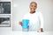 Water, filter and pitcher for woman in kitchen to refresh with glass of liquid hydration. Portrait, happy black female