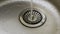 Water flows into a dirty stainless steel metal sink, closeup