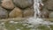 Water flows from the stones into the pond. Small artificial waterfall, rest and meditation, background for text, slow