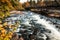 Water flows under bridge surrounded by brilliant fall foliage